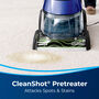 DeepClean Deluxe&trade; Pet Upright Carpet Cleaner Using Clean Shot Feature to spray stain on carpet. Text: CleanShot Pretreater Attacks Spots &amp; Stains