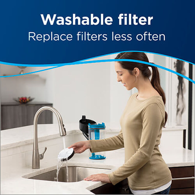 Woman Washing Filter. Text: Washable Filter Replace Filter Less Often.